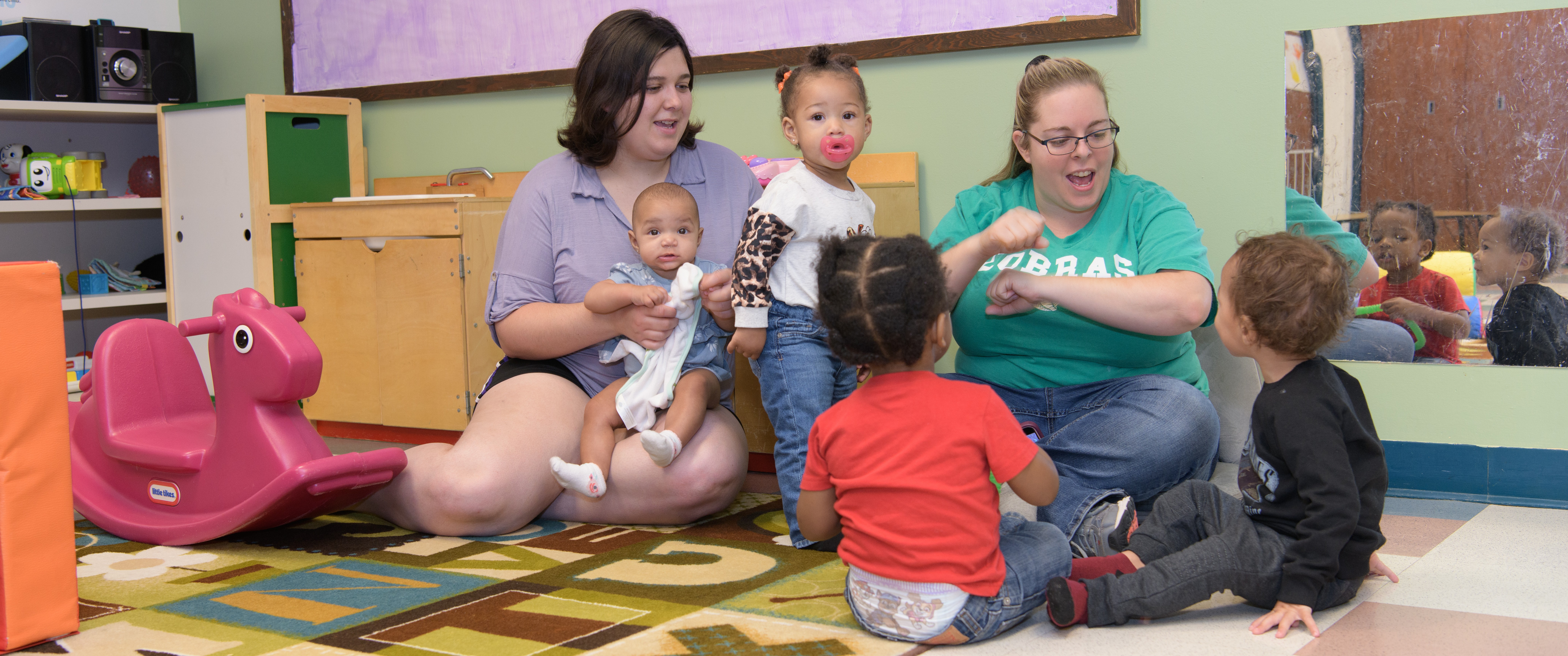 A group of four small children playing with two adults. 