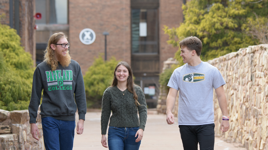 Three students walking outside X Wing