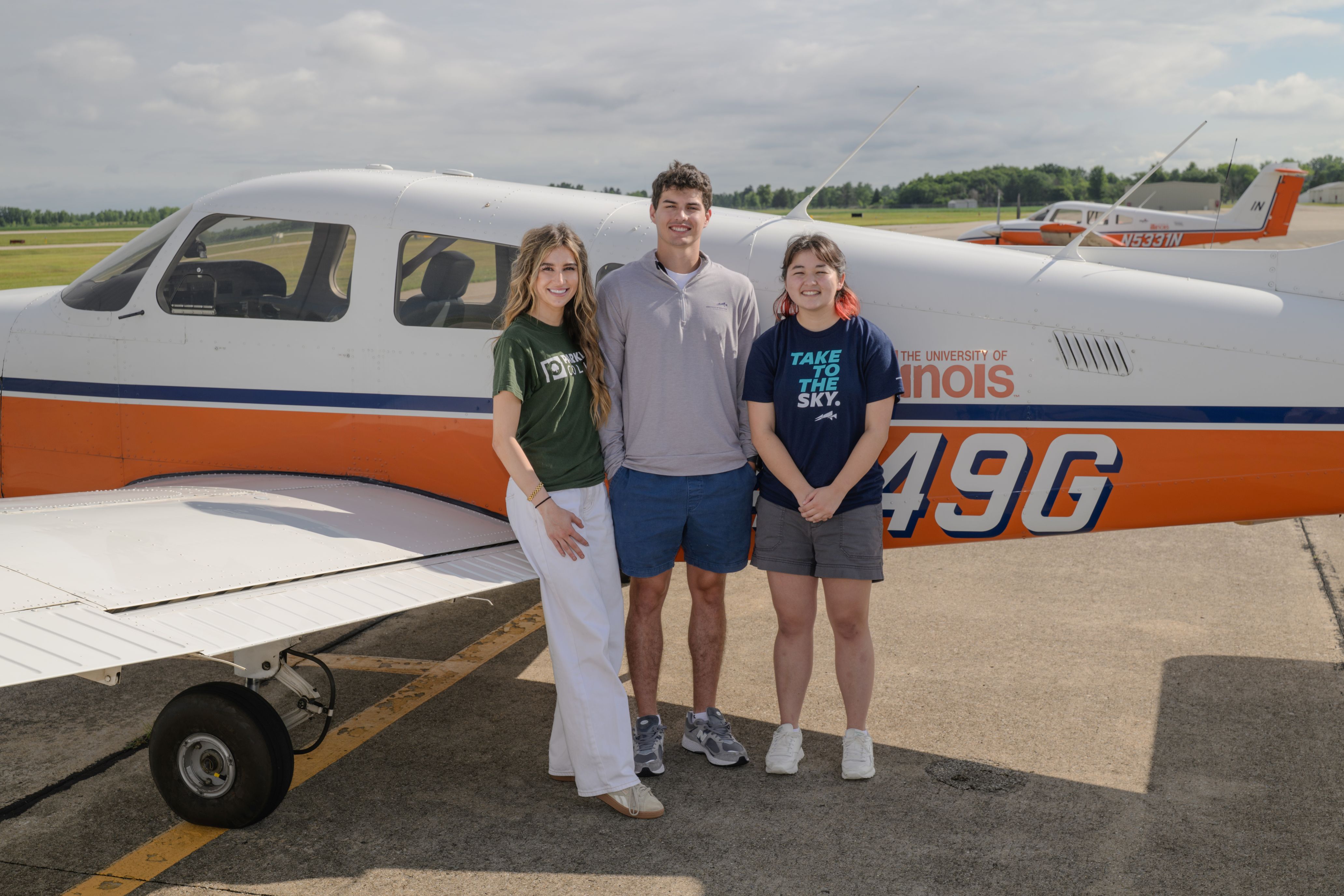 Three Institute of Aviation students standing in front of a plane.