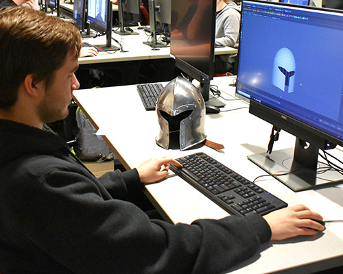 Male student creating 3D model of ancient helmet Male student creating 3D model of ancient helmet