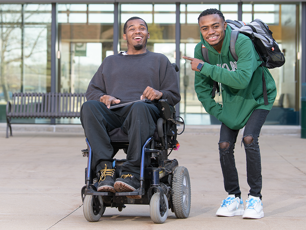 two black men outside one in wheelchair