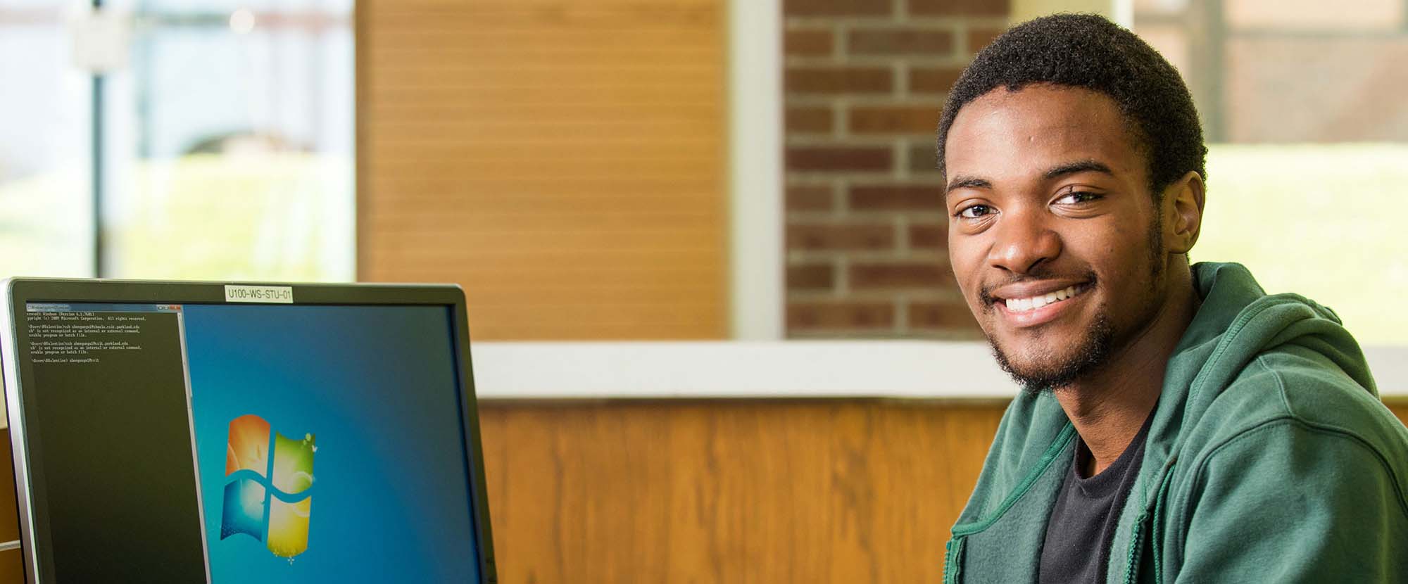 black male student smiling at computer