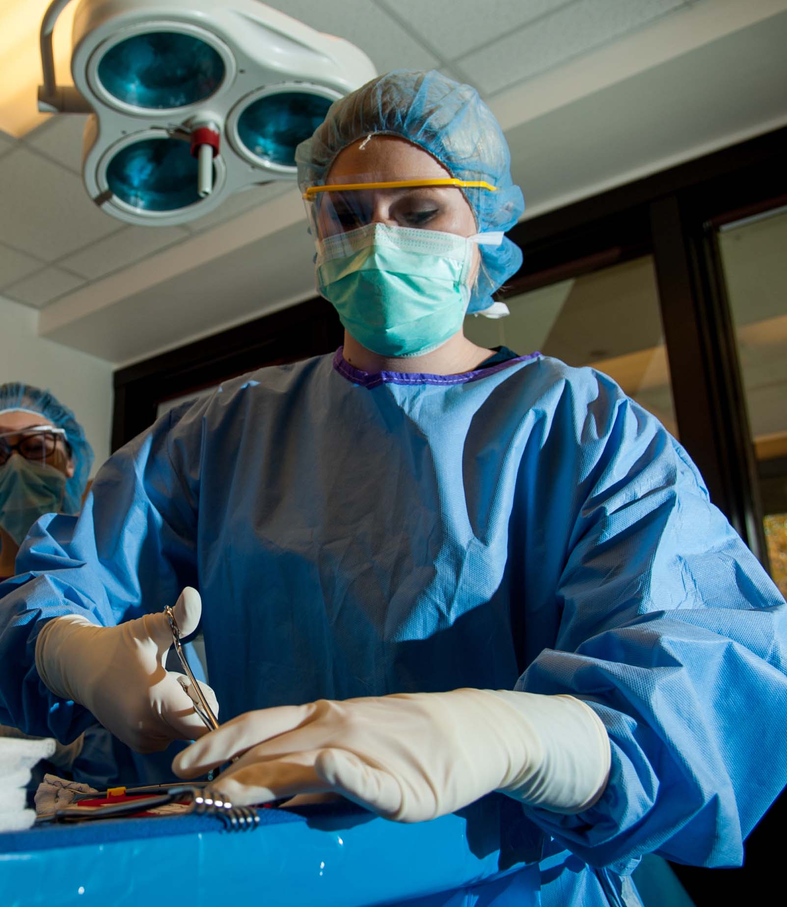 Student in surgical gown holding scissors