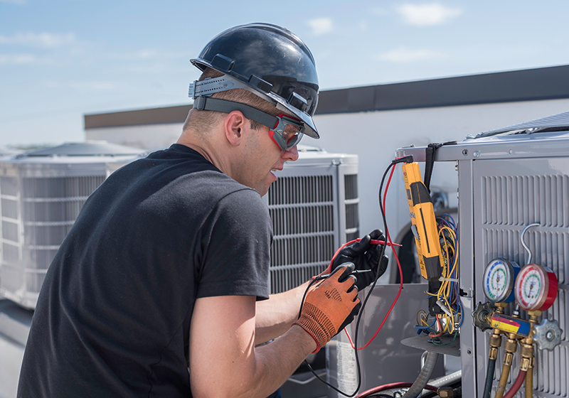 Man in hard hat working on electronic machinery
